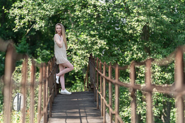 Obraz premium Young Caucasian 20s Woman Standing on a Wooden Bridge in a Lush Forest Setting