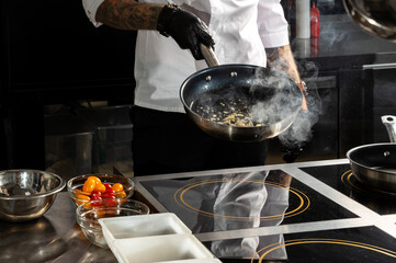 Professional chef cooks shrimps in frying pan with olive oil in restaurant kitchen