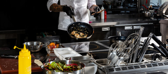 Professional chef cooks shrimps in frying pan with olive oil in restaurant kitchen