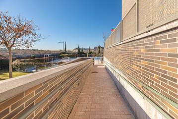 Exterior hallway with terracotta-toned exposed brick walls, natural stone flooring, and climbing vines framing the path.