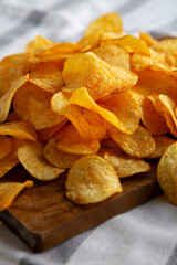 Homemade Flavored Cheese Potato Chips on a Wooden Board, side view.