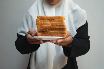 Woman wearing a hijab carries a plate of bread