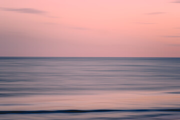 Soft pink sky over still ocean