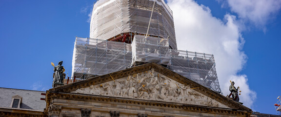 Scaffolding on former municipal building and residence of the royal family called The Palace on the central square De Dam in Amsterdam with dramatic clouds hanging over