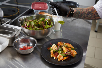 Closeup of chef hands preparing shrimp salad in a luxury restaurant kitchen