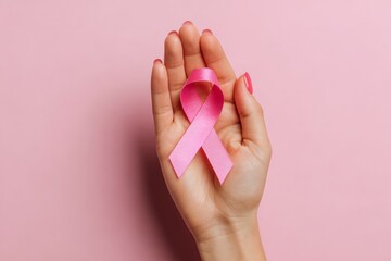 Hand Holding Pink Ribbon on Pink Background for Breast Cancer Awareness