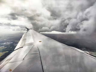 Cloudy skies create a dramatic view from an airplane wing during flight above a landscape