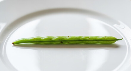 Single fresh green bean on white plate representing healthy food choices and sustainable waste management. This minimalist image highlights organic vegetable and proper nutrition