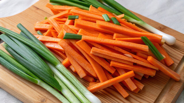 Effective food waste management includes preparing fresh vegetable ingredients. Sliced carrot and spring onion on wooden board ready for healthy cooking meal