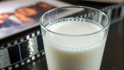 Glass of milk dairy food beside film negative creating nostalgic feeling. reminder of good memories and importance of resource management and avoiding food waste