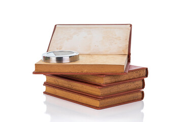 Old vintage book stack with a magnifying glass for research, search, and analysis concepts, isolated on white background with clipping path.