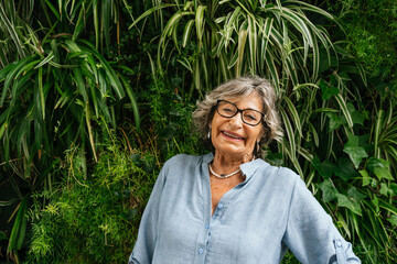Senior woman smiling enjoying green vertical garden