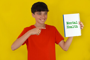 mental health concept. portrait of a smiling teenager with freckles, pointing to a notebook
