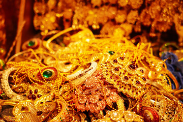 Heap of gold jewelry with red, green gem and diamond. Jewelry with the golden reflect light background.