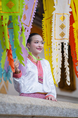 Young woman in traditional Thai attire stands joyfully beneath colorful paper lanterns, showcasing cultural heritage