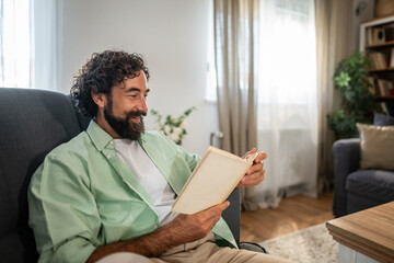 Naklejka premium Happy man relaxing at home reading book