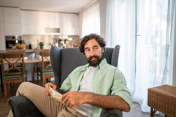 Fototapeta premium Man resting in armchair, reading and unwinding at home