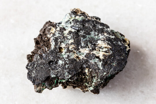 sample of raw tenorite rock on white marble