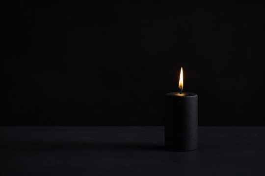 Schwarze Kerze brennt in dunklem Raum, symbolisiert Ruhe und mystische Atmosph&auml;re