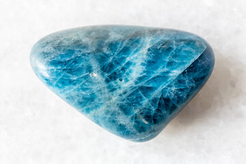 sample of tumbled apatite rock on white marble