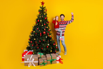 Happy family standing next to a beautifully decorated Christmas tree with gifts, celebrating the joy of the holiday season