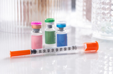 Close up of Vials with Various Injectable Compounds Next to Syringes