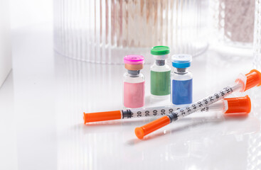 Close up of Vials with Various Injectable Compounds Next to Syringes