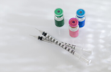 Close up of Vials with Various Injectable Compounds Next to Syringes