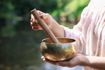 Woman with singing bowl in nature, closeup