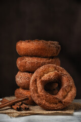 A stack of Fresh made Apple cider Donuts with one leaning on the stack against a mottled dark brown background with copy space.