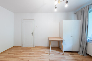 Fototapeta premium Minimalist Living Room with Wooden Desk, White Wardrobe, and Bright Window