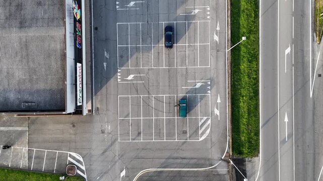Castelvetro Piacentino commercial area seen from above, detailing urban infrastructure with a Prenatal store, expansive parking lot, connecting roads, and passing vehicles