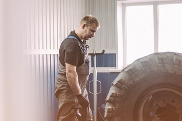 A mechanic is focused on repairing a tire in a well-lit automotive workshop. The setting conveys a...