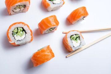 Pieces of delicious japanese sushi frozen in the air. Sushi roll isolated on white background. California sushi roll with tuna, vegetables and unagi sauce closeup
