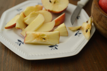 A knife that cut a red apple on a white plate
