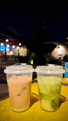 Two refreshing iced drinks on a bright yellow table