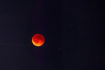 Blood red moon in night sky. Celestial prophecy. Lunar eclipse in dramatic red color with a cosmic sparkle. A symbol of transformation.