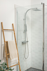 salle de bain blanche avec douche large et serviette posée sur une échelle