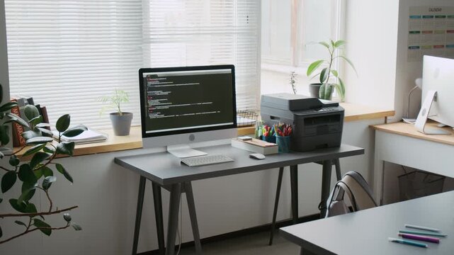 No people shot of organized IT classroom workspace with desk with printer and computer showing code