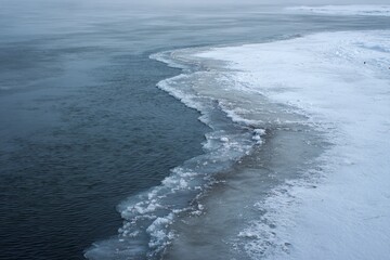 Fototapeta premium A winter scene of frozen shoreline reveals icy textures, calm waters, and coastal beauty. The serene coldness of the landscape emphasizes the quiet majesty of winter’s icy grip, showcasing nature’s
