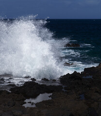 Gran Canaria, north west coast around natural swimming pools Salinas de Agaete, waves breaking against old eroded dark lava platform