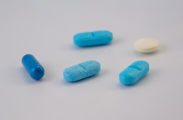 Assorted blue and white pills and capsule on white background, pharmaceutical medicine