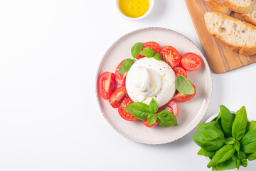 Traditional Italian burrata cheese with salad of delicious cherry tomato, basil leaves and olive oil.