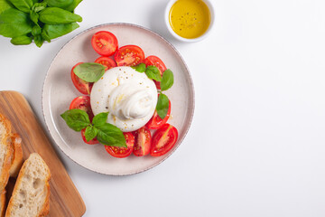 Traditional Italian burrata cheese with salad of delicious cherry tomato, basil leaves and olive oil.