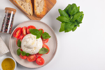 Traditional Italian burrata cheese with salad of delicious cherry tomato, basil leaves and olive oil.