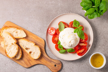Traditional Italian burrata cheese with salad of delicious cherry tomato, basil leaves and olive oil.