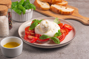 Traditional Italian burrata cheese with salad of delicious cherry tomato, basil leaves and olive oil.
