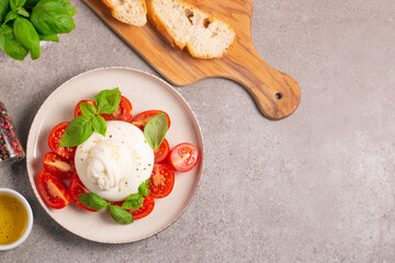 Traditional Italian burrata cheese with salad of delicious cherry tomato, basil leaves and olive oil.