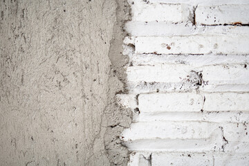 unfinished wall texture with white painted bricks and rough gray cement plaster, construction background useful for design and renovation themes.