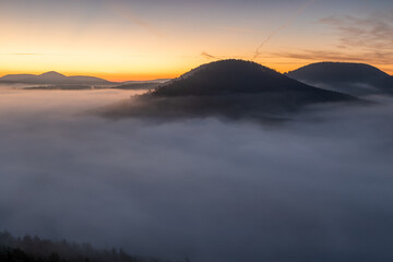 Neblige Täler im Pfälzerwald vom Nesselberg in Lug mit Geiersteinen im goldenen Morgenlicht